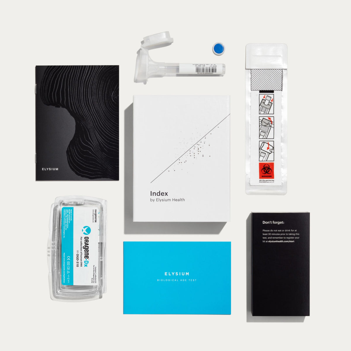 A flat-lay arrangement of Elysium home test kit components on a light gray background, including a black abstract-patterned box, a white instruction booklet, a blue card, a black card, a clear plastic specimen container, and other medical test accessories.