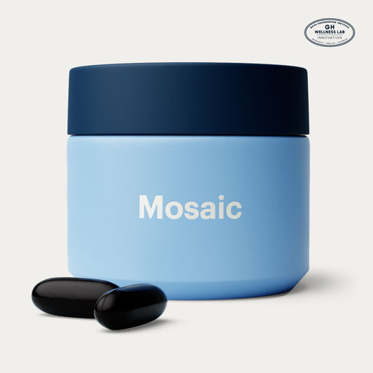 A light blue cosmetic jar of Elysium Mosaic, with two black softgels in front on a light gray background. A circular 'GH Wellness Lab' logo is visible in the top right corner.