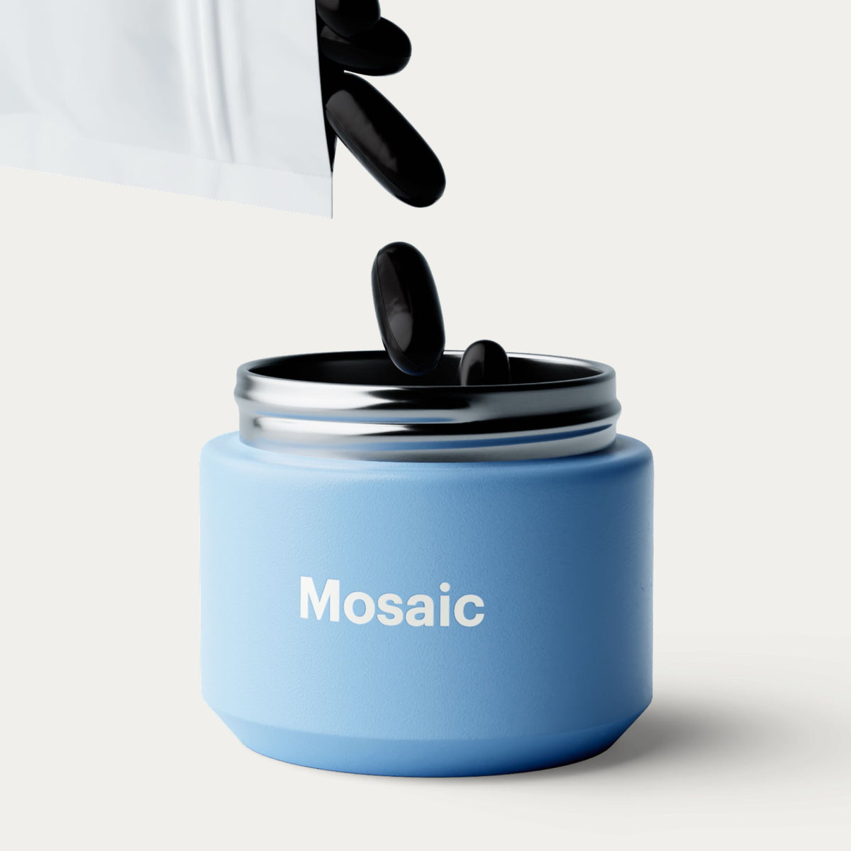 A light blue cosmetic Mosaic jar with a metallic silver lid, shown on a clean off-white background. Black softgels are being poured from a white pouch into the open jar.