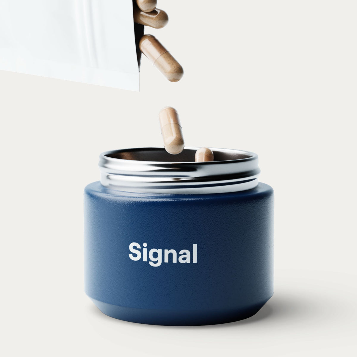 A matte navy blue cylindrical supplement jar with a silver rim and the word 'Signal' printed in white on the front. Capsules are shown falling into the open jar from a white pouch against a clean off-white background.