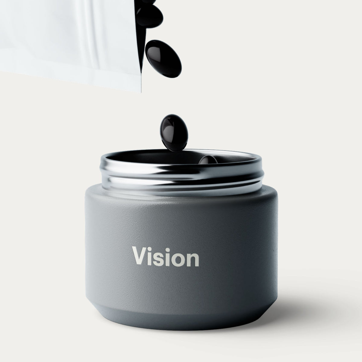 A matte dark gray cosmetic jar labeled 'Vision' with a metallic silver lid, shown open with glossy black softgels being poured above it on a clean light background.