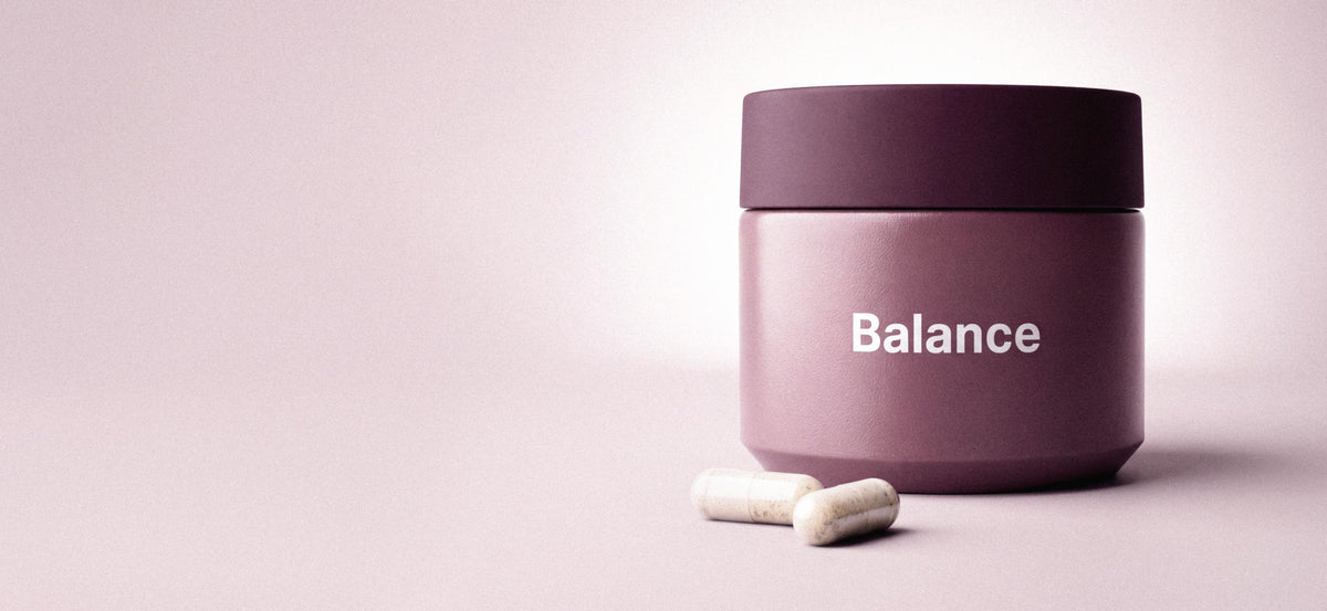 Balance jar with two capsules on a soft mauve background